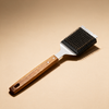 Long handle barbecue grill brush with scraper on a warm beige studio backdrop