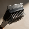 Close-up of the stainless steel bristles and scraper edge on the grill brush head