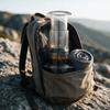 Portable coffee press packed in a backpack pocket outdoors