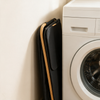 Laundry basket collapsed flat and leaning against a wall beside a washing machine
