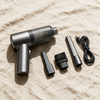 Car vacuum laid out with its crevice tool, brush head, extension nozzle and cable
