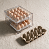 Egg container holding 24 eggs next to an empty ten-egg cardboard carton, showing the fridge space it saves
